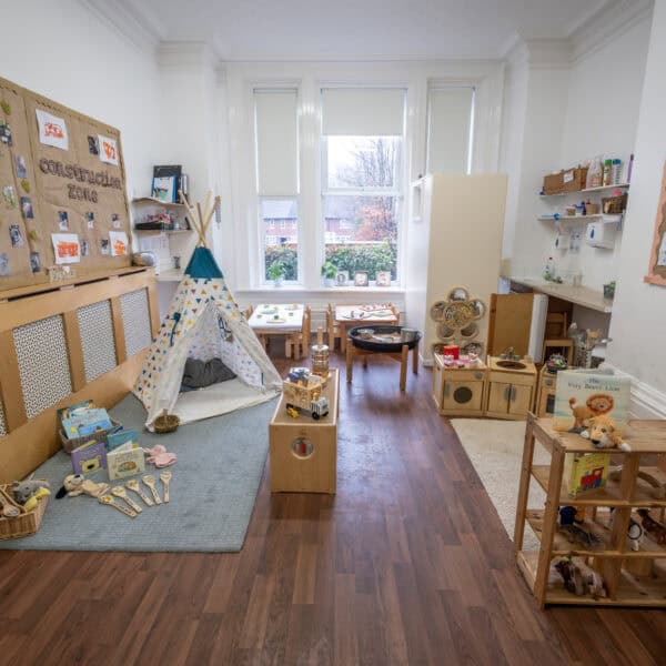 Bright indoor children’s playroom with wooden furniture, toys, books, and educational displays, fostering early childhood development and childcare at Thrive Childcare.