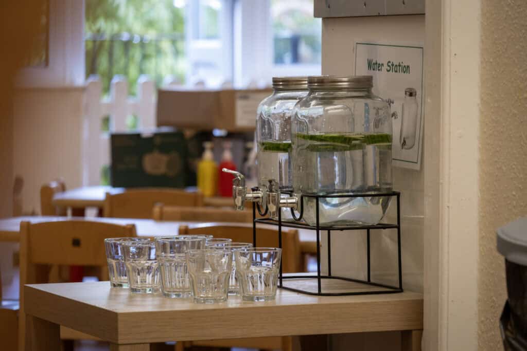 Refreshing water station with jars of infused water in a colourful childcare setting for kids.