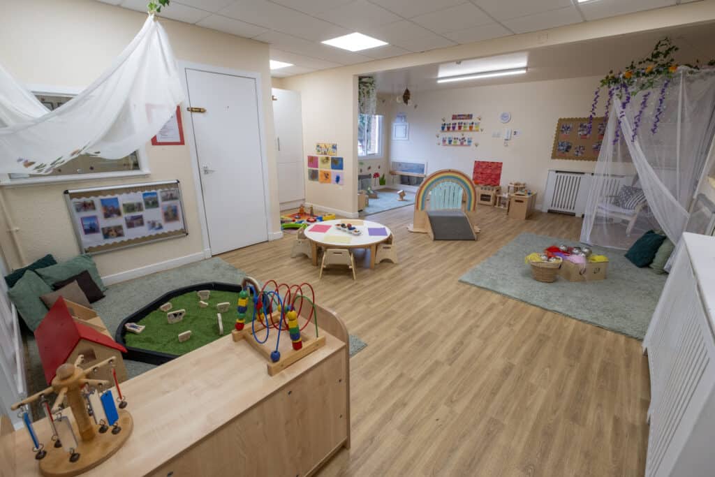 Bright indoor childcare playroom with toys, activities, and soft mats, promoting early childhood development in a safe and engaging environment at Thrive Childcare.