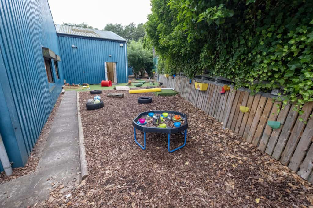 Bright outdoor childcare play area at Thrive Childcare with toys, play equipment, and natural surroundings, ideal for children’s development and outdoor fun.