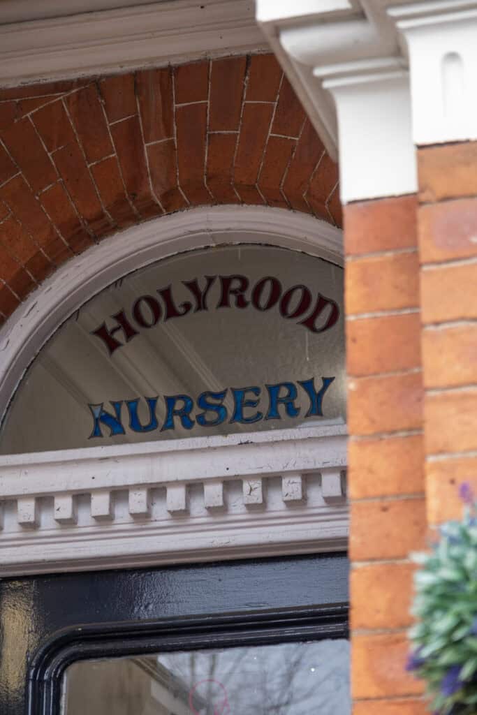 Bright red brick arch above nursery entrance with "Hollyrood Nursery" sign, showcasing welcoming childcare environment and early learning centre.