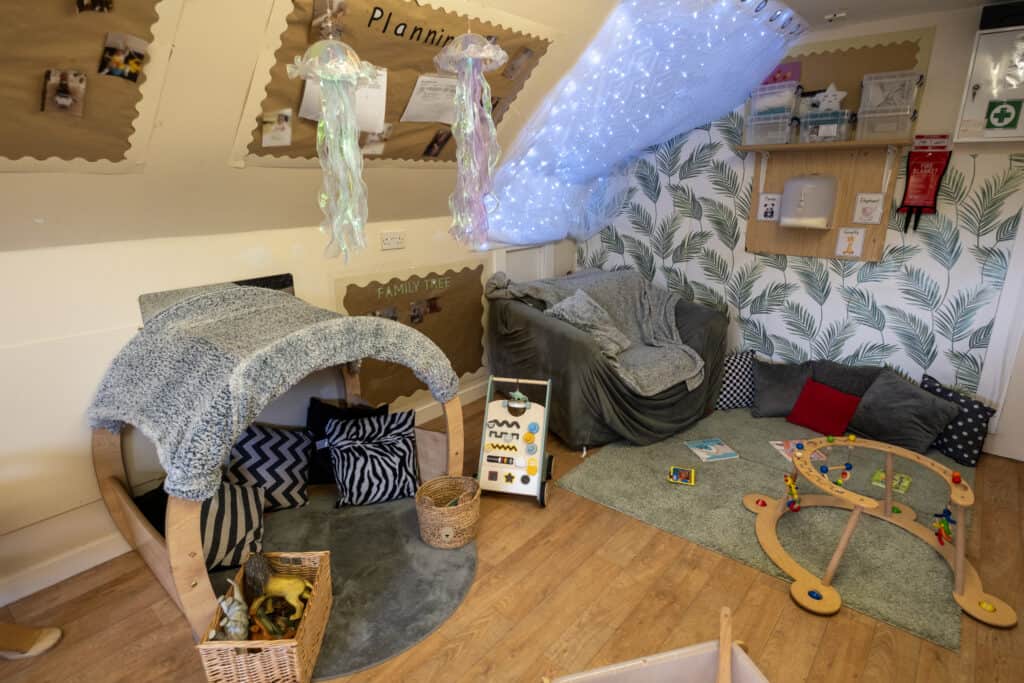 Soft play area with cozy seating, sensory toys, and colourful wooden play structures in a welcoming childcare environment. Perfect for nurturing early childhood development.