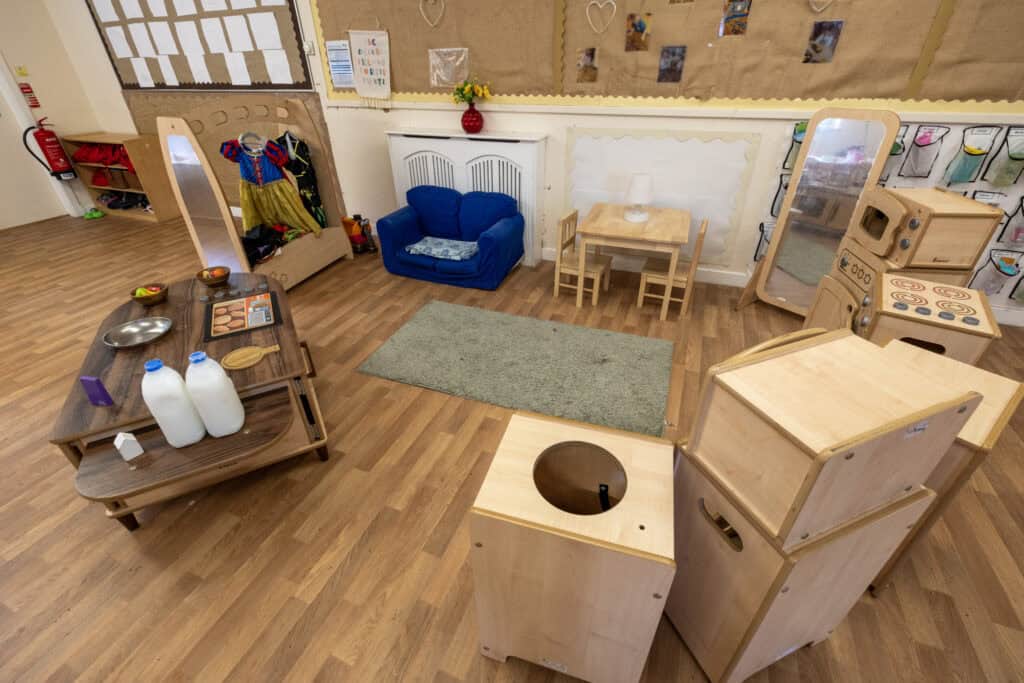 Learning through play at Thrive Childcare, featuring a cosy reading nook, wooden toys, imaginative dress-up area, and child-friendly play kitchen to support early childhood development and creativity.