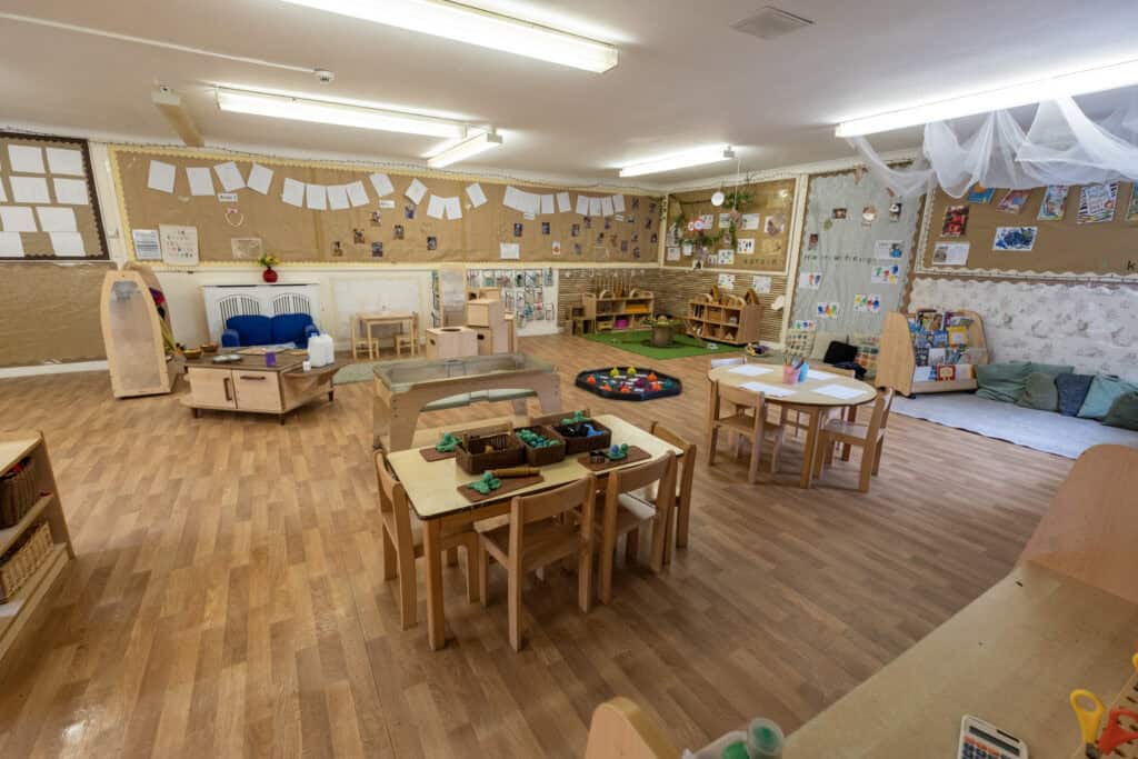 Bright, spacious indoor play area at Thrive Childcare featuring children's tables, educational toys, reading corners, and comfortable cushions for a nurturing early learning environment.