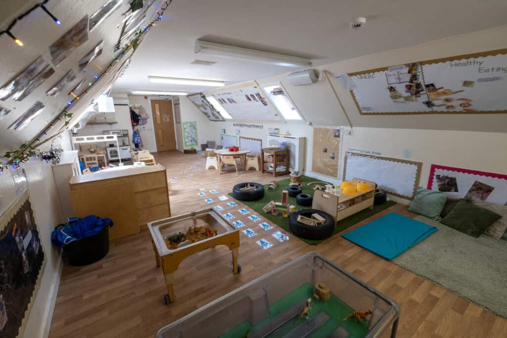 Bright, welcoming indoor childcare room with play areas, educational posters, sensory toys, and comfortable resting spots, ideal for early childhood development at Thrive Childcare.