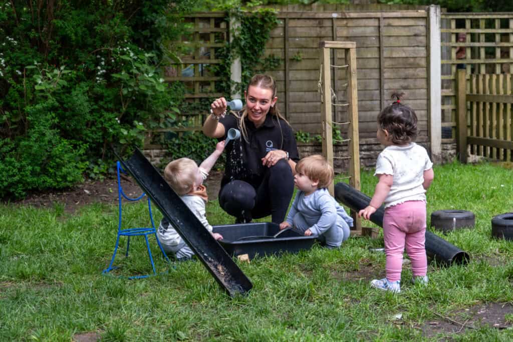 Children's outdoor play at Thrive Childcare, engaging with a caregiver, exploring water activities, and enjoying a safe, nurturing environment for early childhood development.