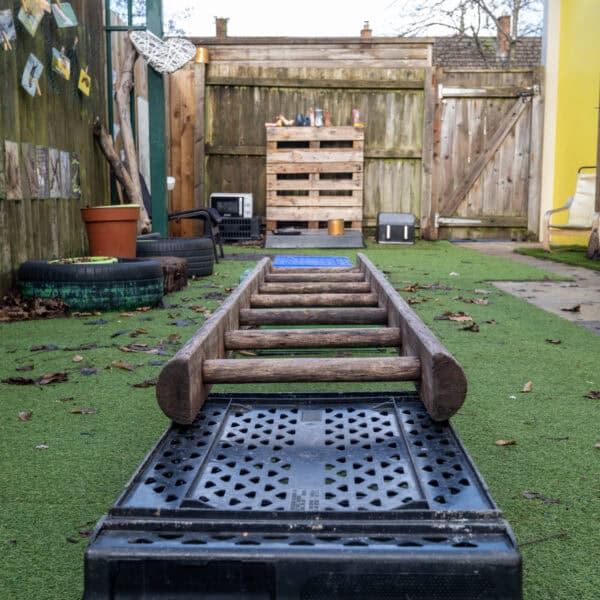Climbing obstacle course in an outdoor childcare playground at Thrive Childcare, featuring wooden ladders and rubber flooring for safe play and physical development.