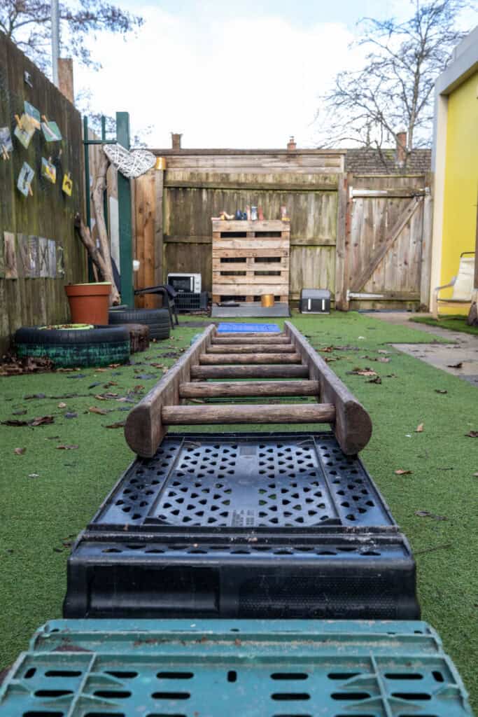 Climbing obstacle course in an outdoor childcare playground at Thrive Childcare, featuring wooden ladders and rubber flooring for safe play and physical development.
