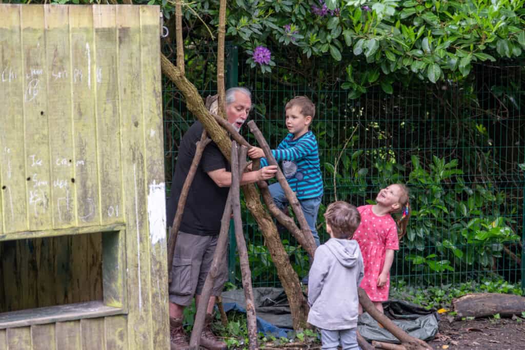 Aerial view of children and caretaker engaging in outdoor creative play at Thrive Childcare, encouraging imagination and social development in a safe, natural environment.