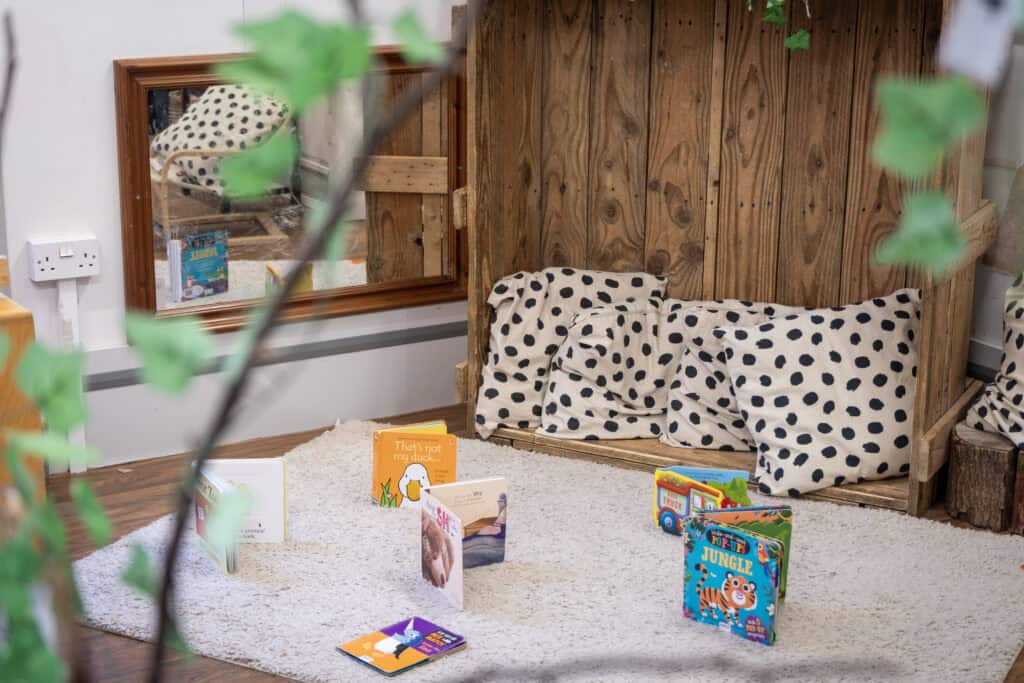 Newborn reading nook at Thrive Childcare with soft cushions, wooden privacy screen, and children's books to encourage early literacy and comfort for young children.