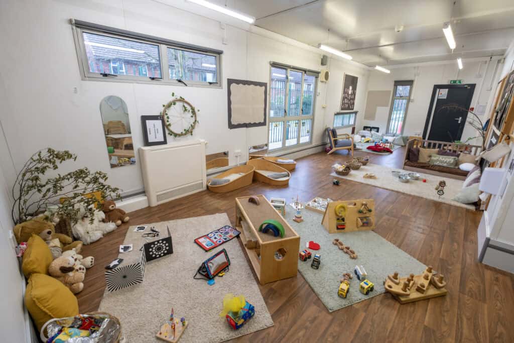 Bright, spacious indoor play area at Thrive Childcare with soft rugs, toys, and play stations, designed for early childhood development and safe, engaging activities for young children.