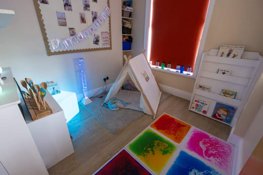 Bright and inviting childcare playroom at Thrive Childcare featuring colourful sensory mats, children's books, and a cozy tent for imaginative play, designed for early childhood development and learning.