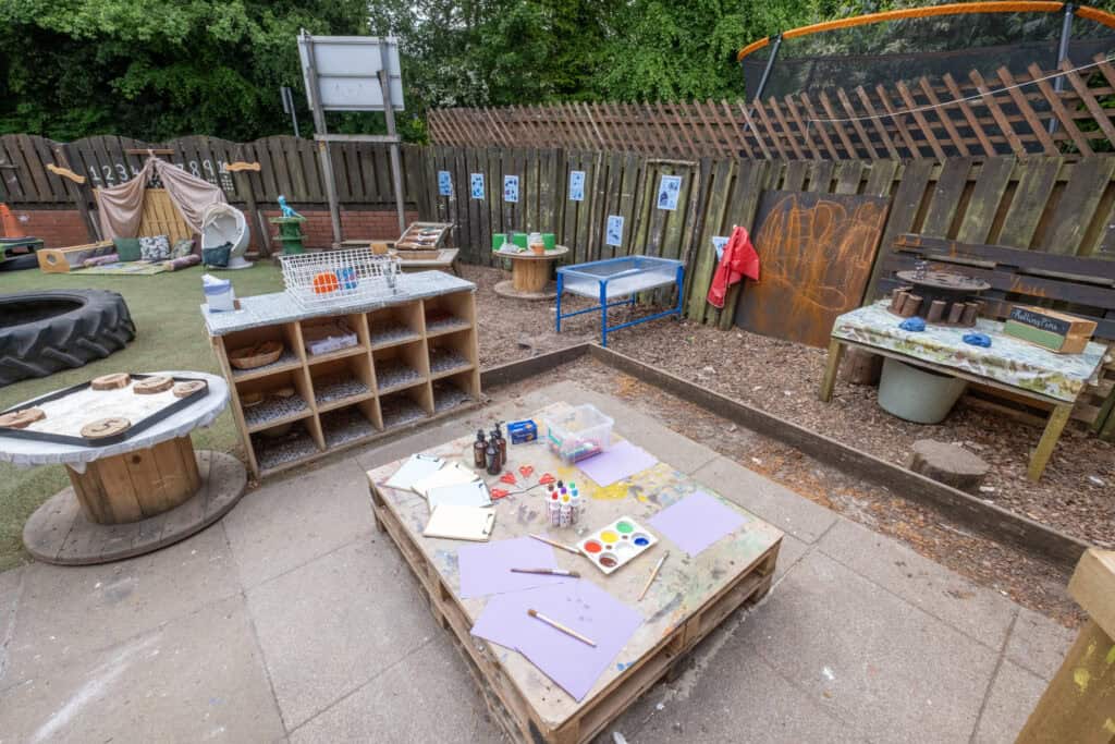 Colourful outdoor play and craft area at Thrive Childcare, featuring painting supplies, sensory tables, and creative zones for early childhood development and fun learning activities.