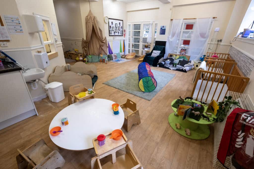 Bright indoor childcare play area with toys, cosy reading nooks, activity stations, and soft mats for young children, promoting a nurturing environment at Thrive Childcare.