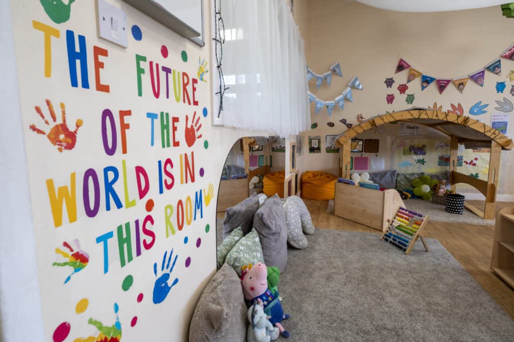 Colourful children's playroom at Thrive Childcare with cosy reading nook, soft toys, and educational wall decorations, fostering a safe and stimulating environment for early childhood development.