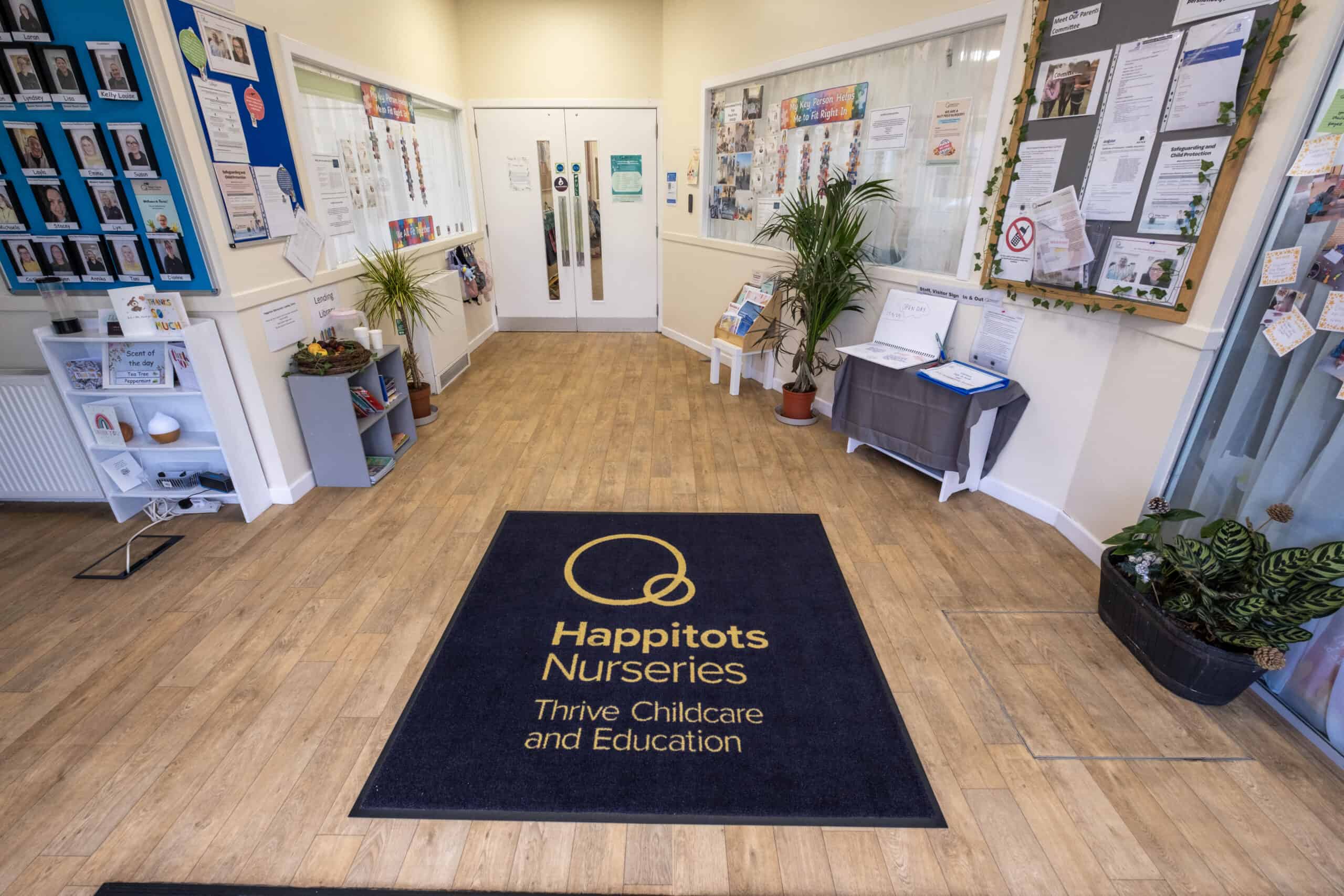 Bright nursery reception area of Thrive Childcare with welcoming decor, childcare information, and a branded mat, showcasing a safe and engaging environment for young children and parents.