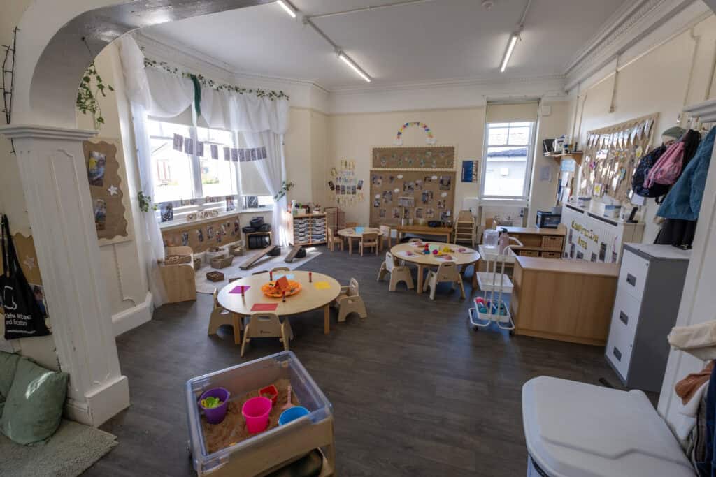 Bright and spacious Thrive Childcare indoor play area with child-sized tables, educational toys, and colourful decorations promoting early childhood development and learning.