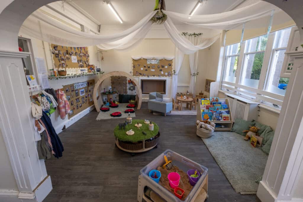 Bright and welcoming childcare indoor playroom at Thrive Childcare showcasing space for learning, creativity, and play with cozy seating, educational books, and imaginative toys.