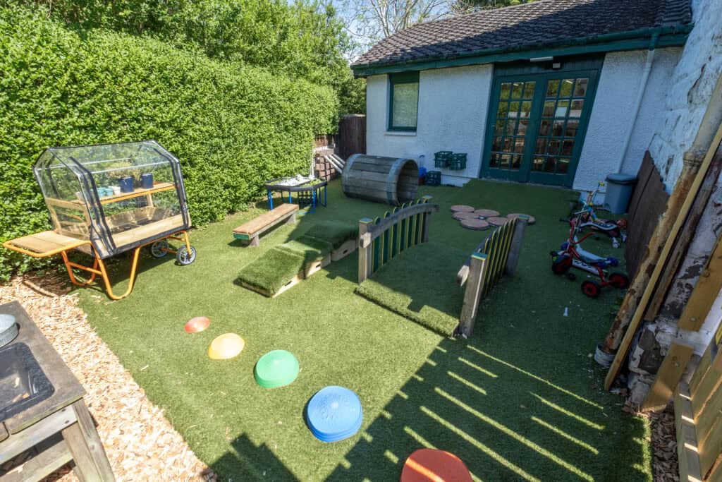 Bright outdoor play area at Thrive Childcare with padded toys, climbing frames, and green space for children’s fun and development. Perfect for outdoor learning and active play in a secure environment.