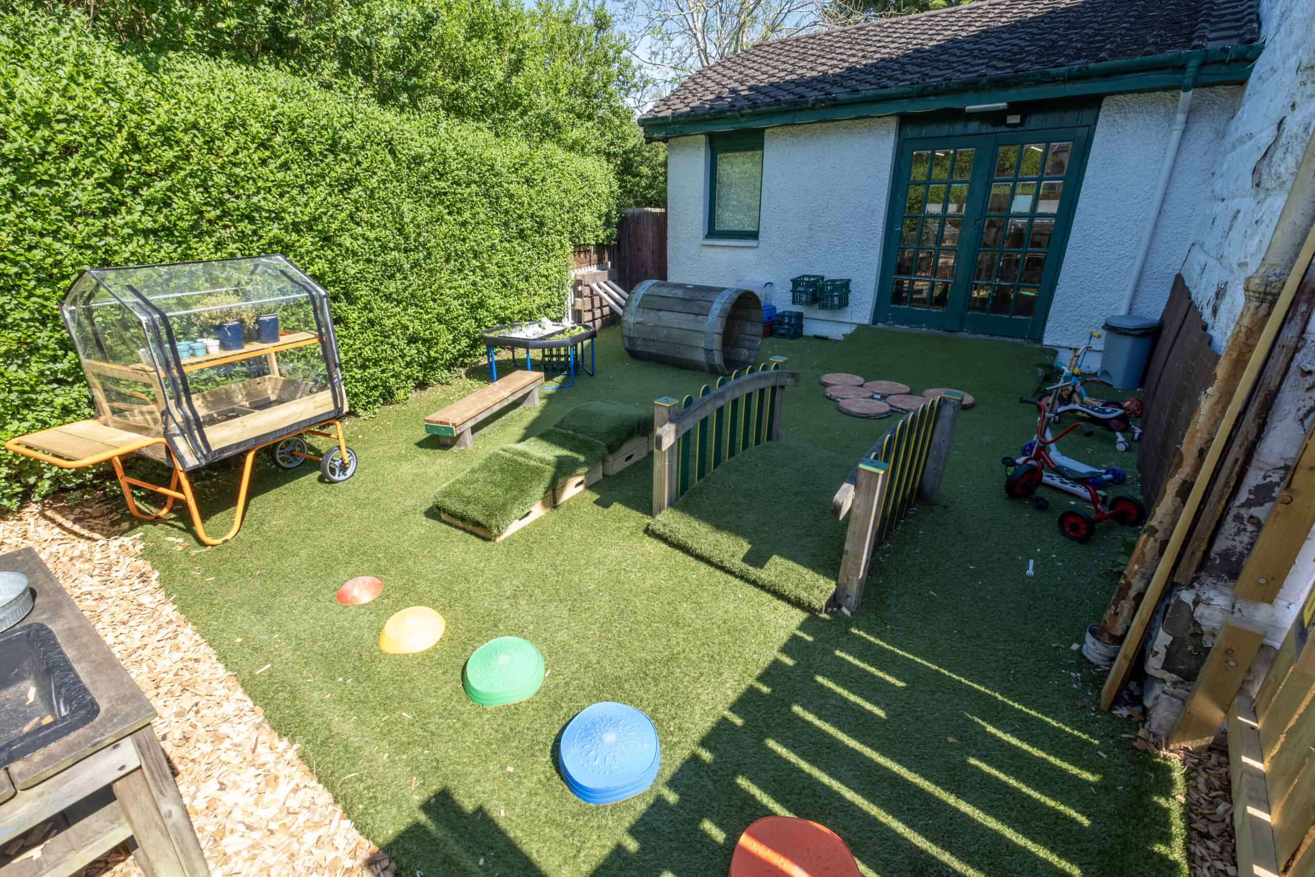 Bright outdoor play area at Thrive Childcare with padded toys, climbing frames, and green space for children’s fun and development. Perfect for outdoor learning and active play in a secure environment.