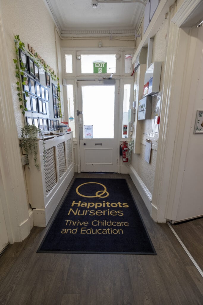 Bright nursery entrance with Thrive Childcare branding, welcoming atmosphere, and safety equipment, ideal for early years education and childcare services in a warm, family-friendly environment.