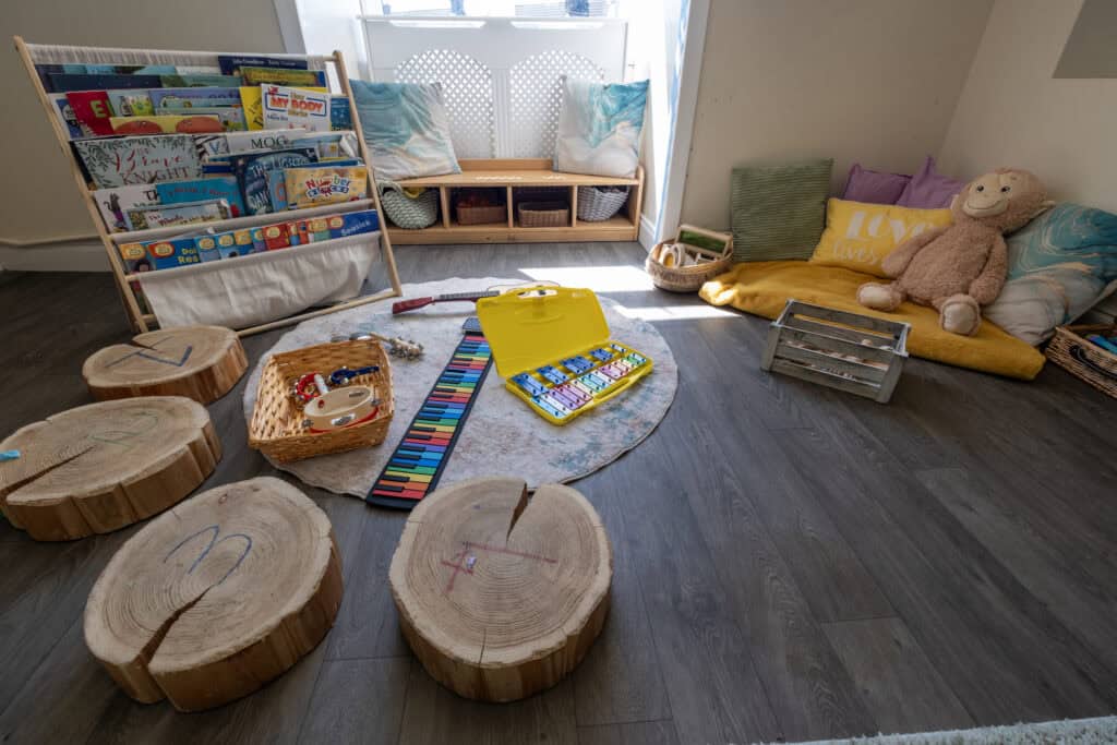 Interactive early childhood classroom setup at Thrive Childcare with book displays, soft cushions, musical toys, and natural wood elements for a nurturing learning environment.
