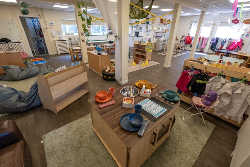 Bright and welcoming indoor childcare environment with play areas, educational toys, and dining setup at Thrive Childcare, promoting early learning and development for children.
