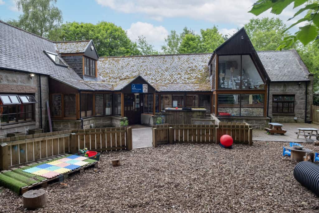 Bright outdoor play area at Thrive Childcare with wood chips, toys, and safe fencing, providing a nurturing environment for children's outdoor activities and discovery.