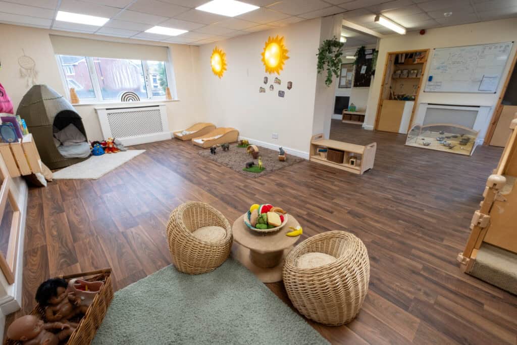 Bright and welcoming Thrive Childcare indoor play area with wooden flooring, soft toys, and educational displays, designed for preschool children to learn, play, and develop in a safe environment.