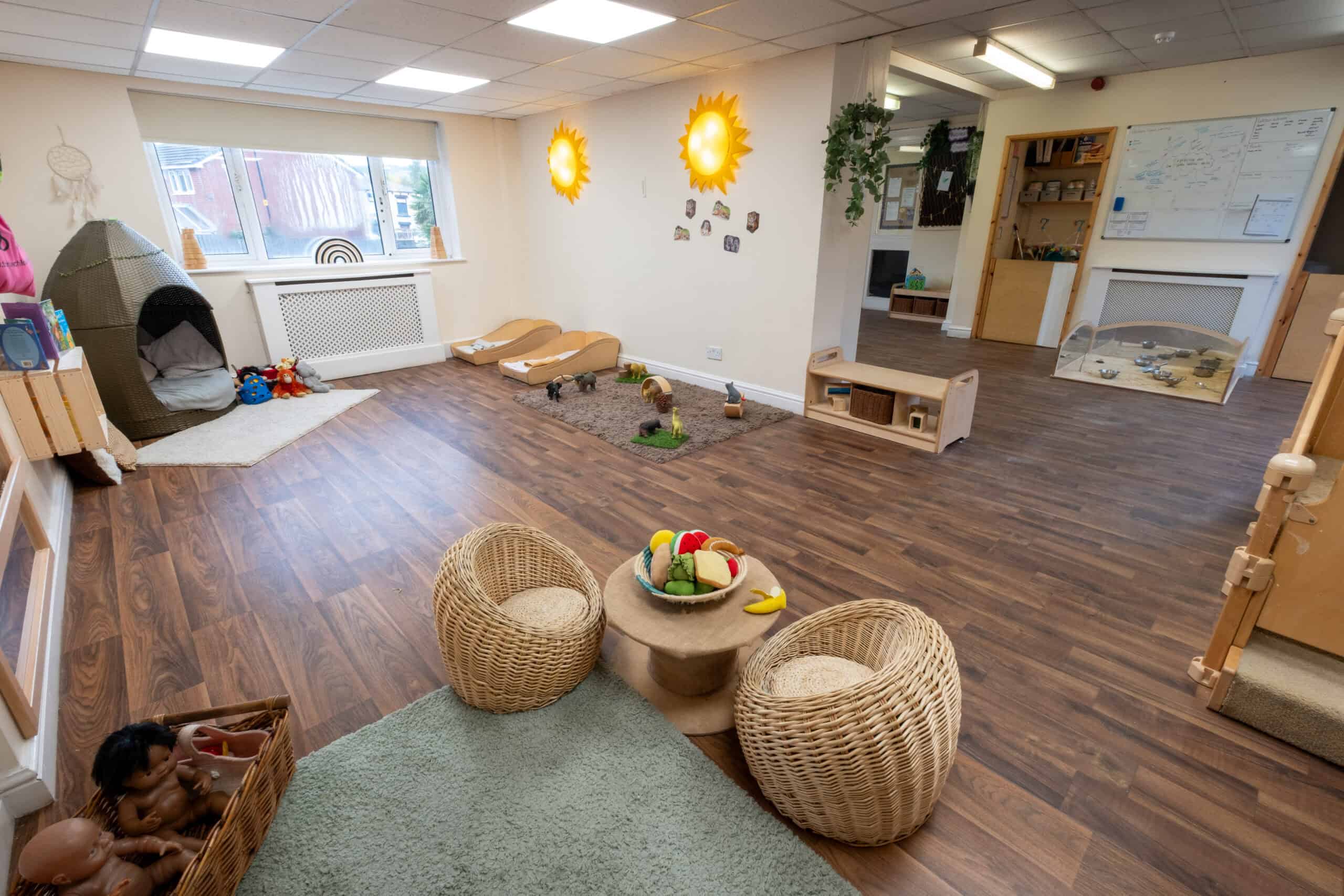 Bright and welcoming Thrive Childcare indoor play area with wooden flooring, soft toys, and educational displays, designed for preschool children to learn, play, and develop in a safe environment.