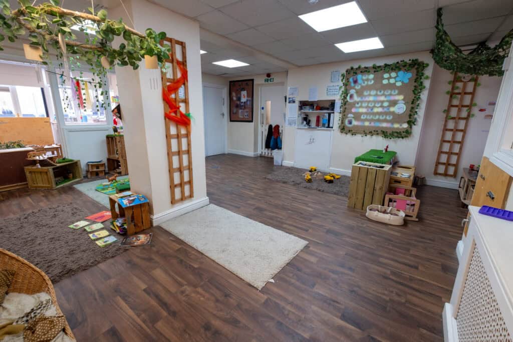Bright and inviting Thrive Childcare indoor play area with natural wood furniture, sensory decorations, and ample space for children to learn and play safely.
