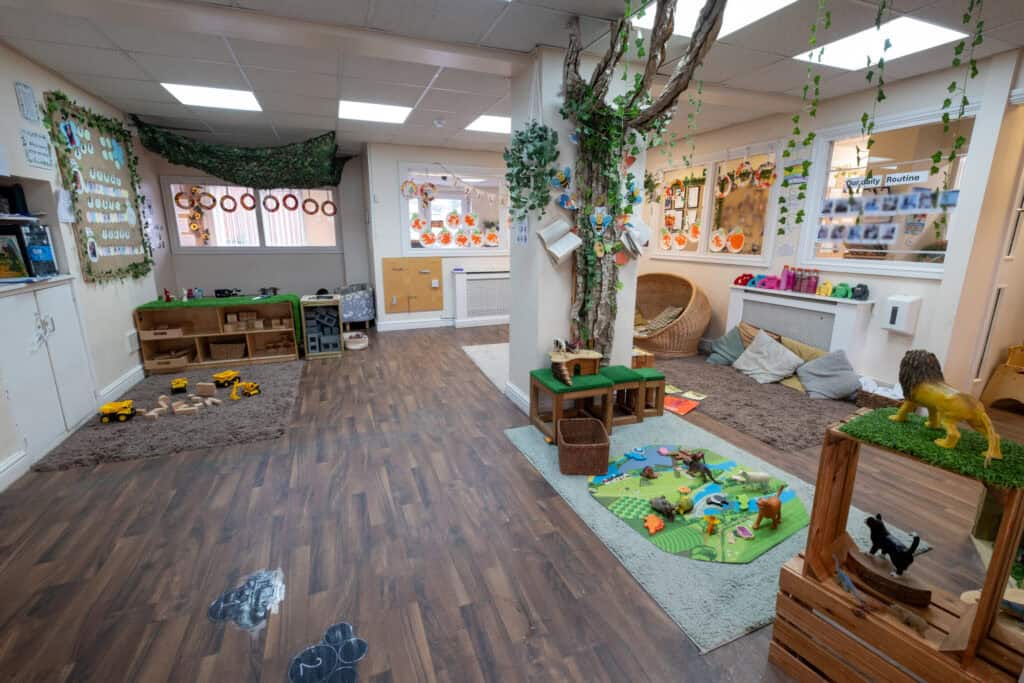 Colourful indoor childcare play area with toys, trees, and learning materials at Thrive Childcare in the UK, creating a nurturing environment for young children’s development and early education.