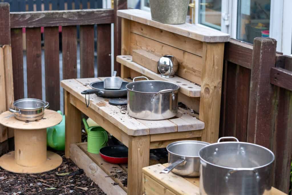 1. Outdoor play kitchen for children with pots, pans, and utensils, encouraging imaginative play and social interaction at Thrive Childcare.
