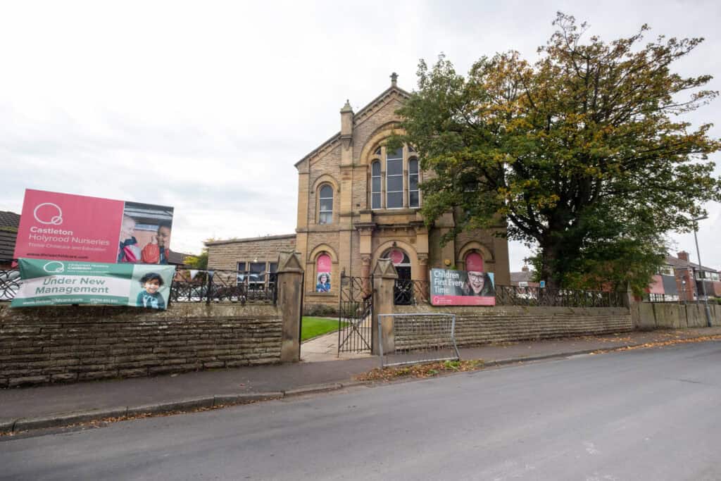 Bright, historic church building serving as Thrive Childcare facility with signage highlighting nursery and education services in Castleton, under new management, colourful exterior, and surrounding trees.