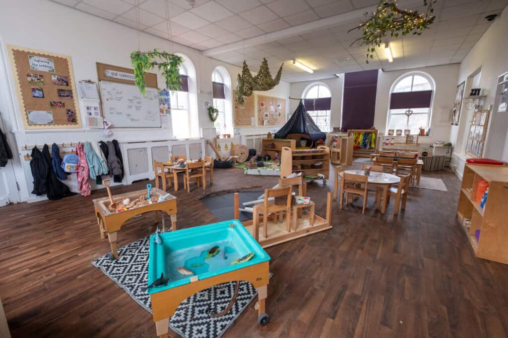 Bright, spacious Thrive Childcare indoor playroom with educational toys, sensory activities, and dress-up area, supporting early childhood development in a friendly environment.
