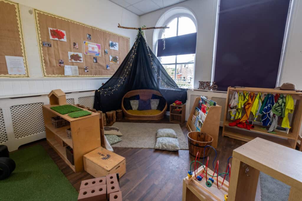 Bright indoor childcare play area at Thrive Childcare with cozy seating, educational toys, and colourful safety jackets, creating a safe, engaging environment for young children.
