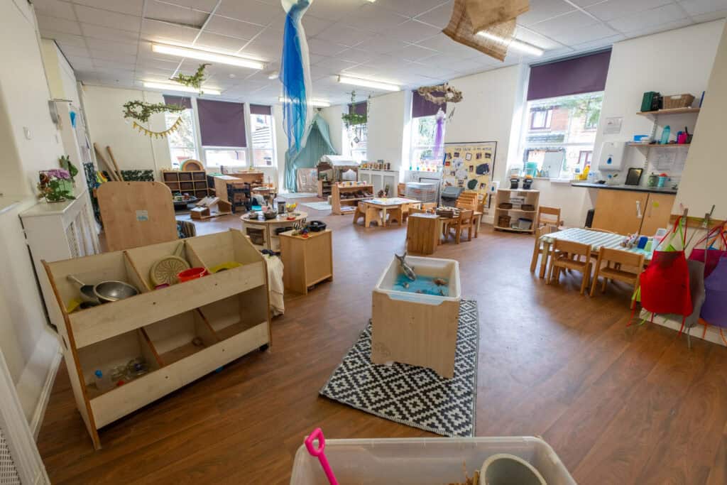 Bright and welcoming childcare indoor play area with wooden furniture, sensory stations, and natural light, designed for early childhood development at Thrive Childcare.