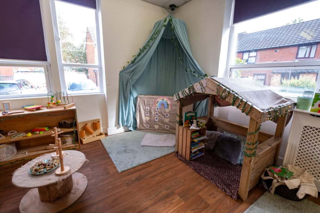 Bright and inviting childcare play area with wooden toys, cosy reading nook, and creative DIY playhouse, perfect for children's learning and development at Thrive Childcare.