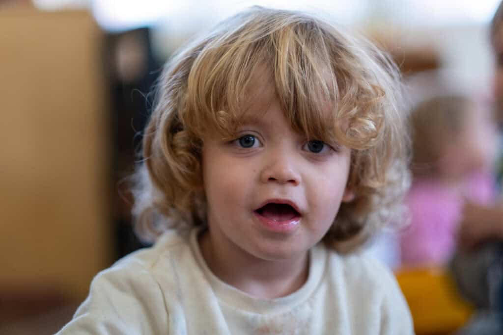 Playful young child with curly blonde hair at Thrive Childcare, engaging in early childhood education and development activities in a nurturing learning environment.