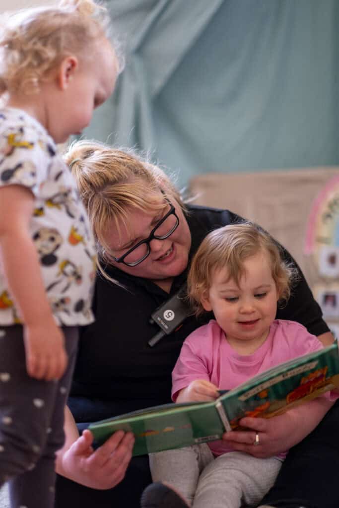 Bright, caring childcare worker engaging with young children in a nurturing environment at Thrive Childcare, promoting early childhood development and learning.