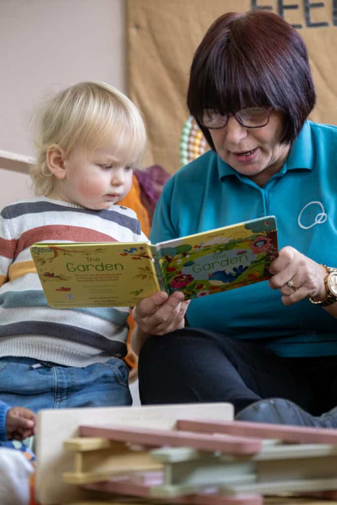 1. Caregiver reading a colourful children's book to a young child at Thrive Childcare, fostering early literacy and development.
