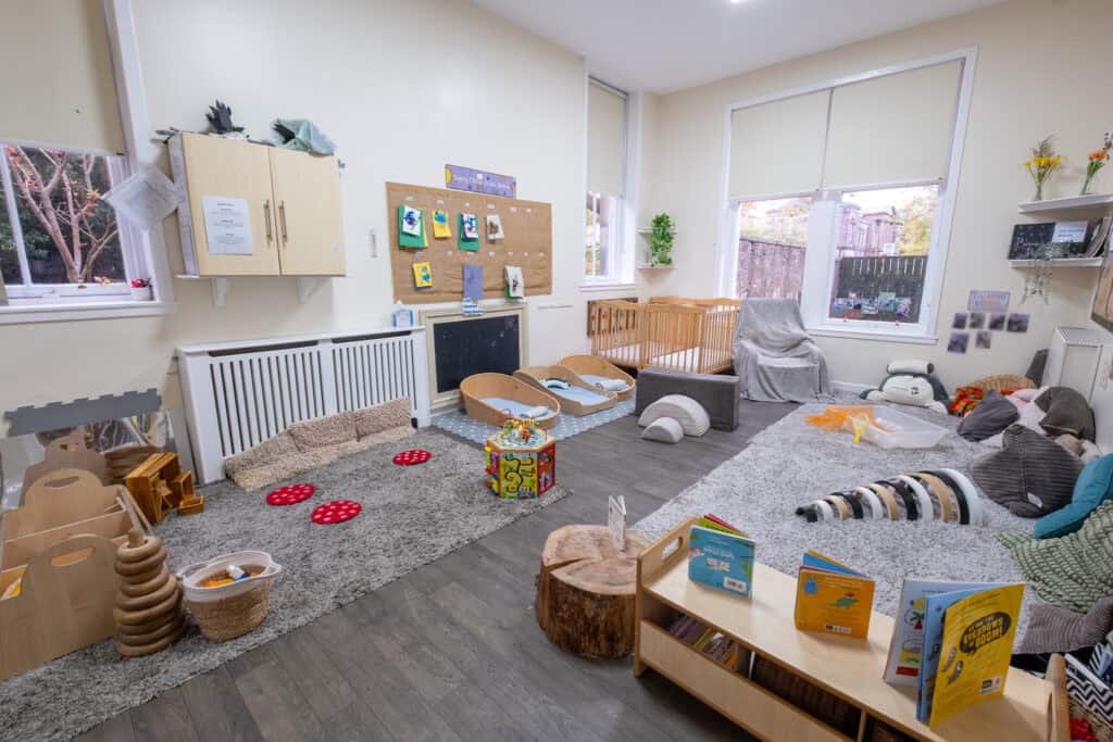 Bright indoor nursery space with soft mats, toys, and children's books for early childhood development and play at Thrive Childcare.