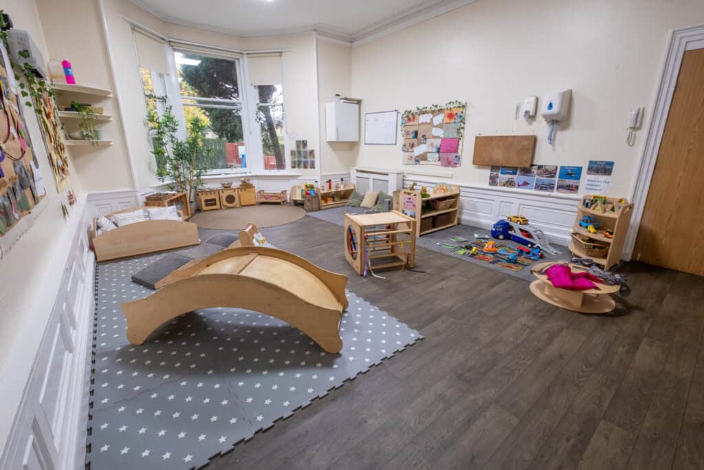 Bright and welcoming childcare indoor play area at Thrive Childcare, featuring wooden toys, cosy cushions, and colourful educational materials for preschool children.