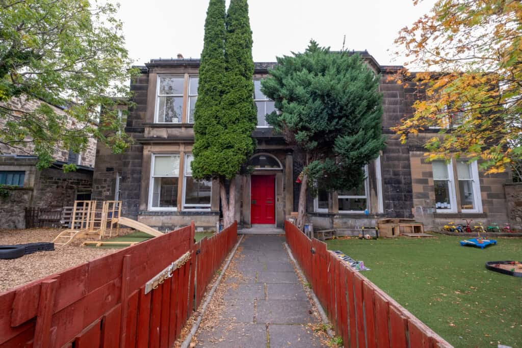 Bright, welcoming childcare centre entrance with colourful outdoor play area and lush trees, promoting a safe and engaging environment for children's growth and development at Thrive Childcare.
