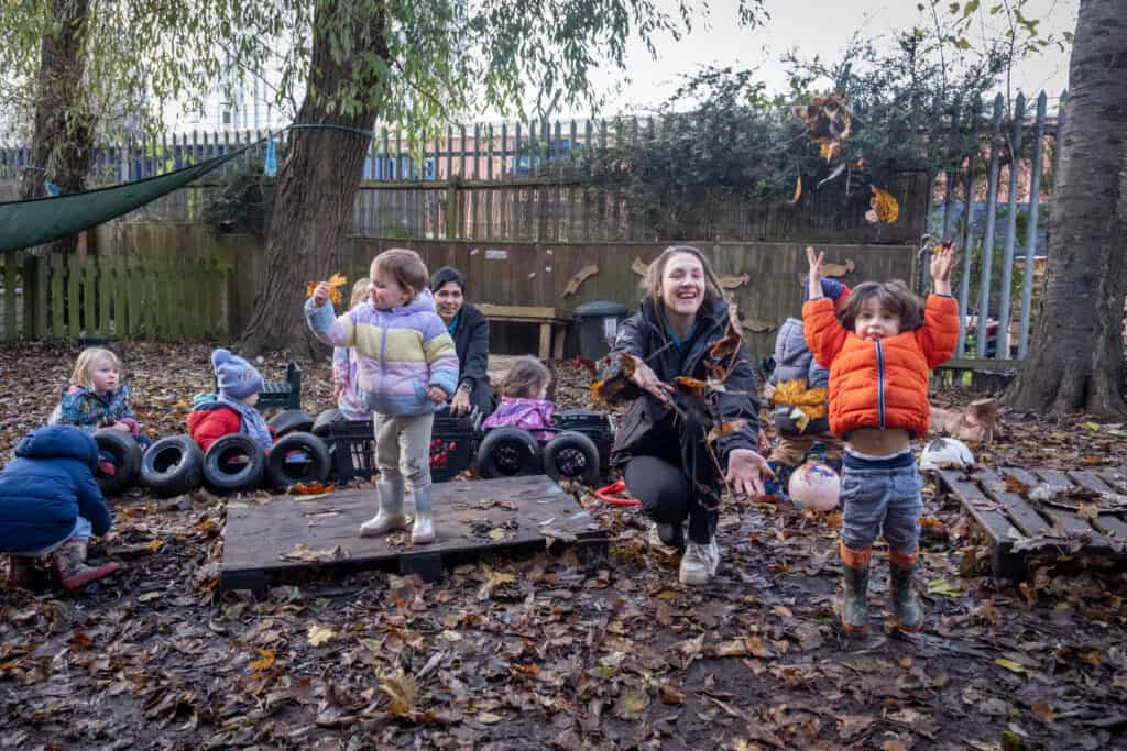 Colourful preschool children playing outdoors in autumn leaves at Thrive Childcare, engaging in educational and fun nature activities for early childhood development.