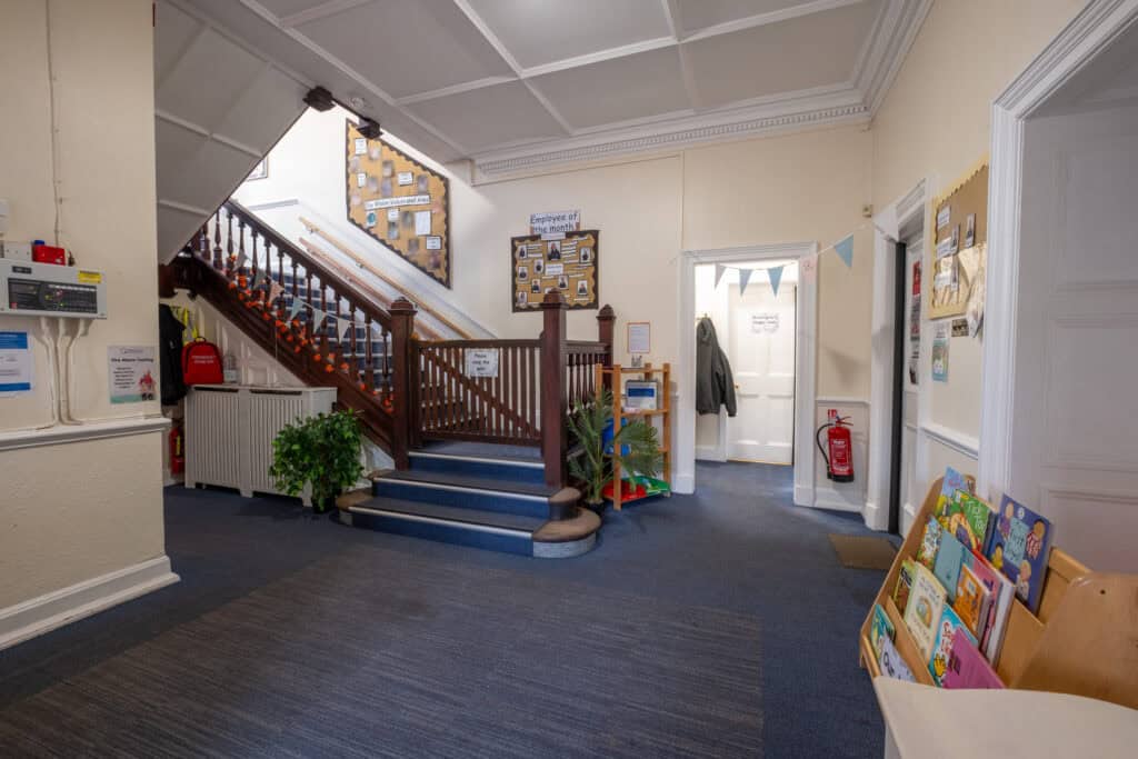 Bright childcare centre entrance with welcoming reception area, vibrant children's books, and informative display boards, showcasing a safe and nurturing environment for young children at Thrive Childcare.
