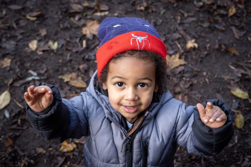 Child playing outside in nature at Thrive Childcare, engaging in outdoor activities and environmental exploration, promoting childhood development and outdoor learning.