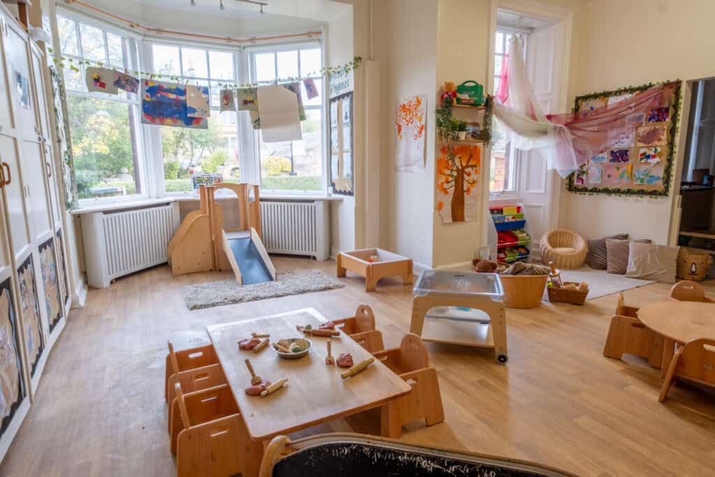 Bright childcare indoor playroom at Thrive Childcare featuring toddler furniture, art displays, and sensory areas for young children’s learning and development.