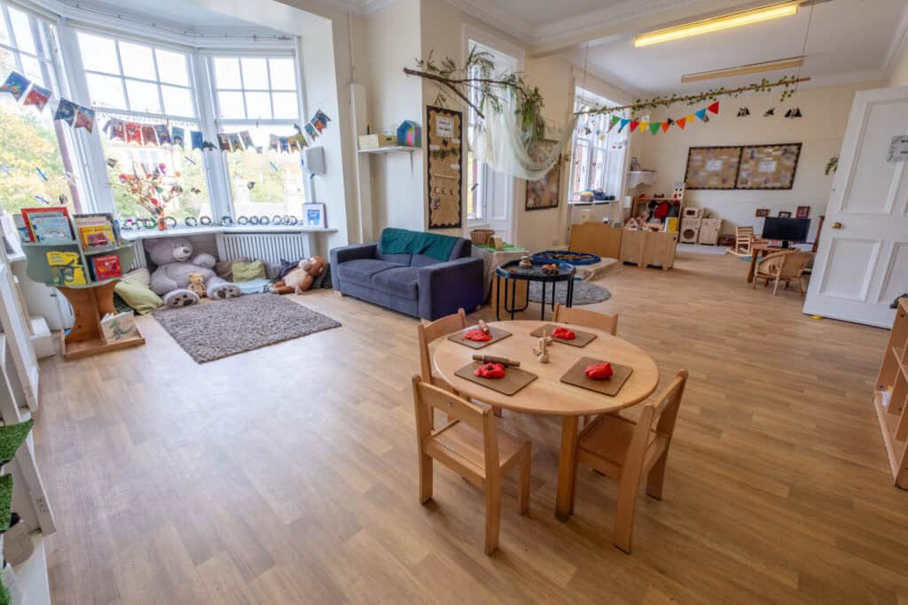 Bright, welcoming childcare indoor play area at Thrive Childcare featuring cozy reading corner, toy shelves, arts and crafts table, and interactive learning spaces for young children.