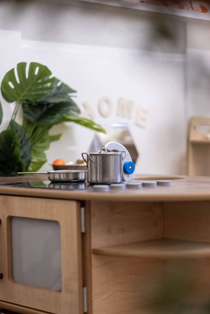 Bright children's play kitchen with stainless steel pots and pans, promoting imaginative play and learning at Thrive Childcare. Perfect for early childhood development and creativity.